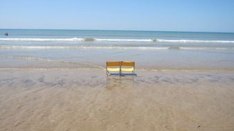 two yellow chairs stand on the beach in France