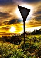 attention, traffic sign right of way in countryside at sunset