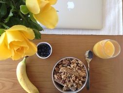 granola with banana and berries and a glass of orange juice for breakfast