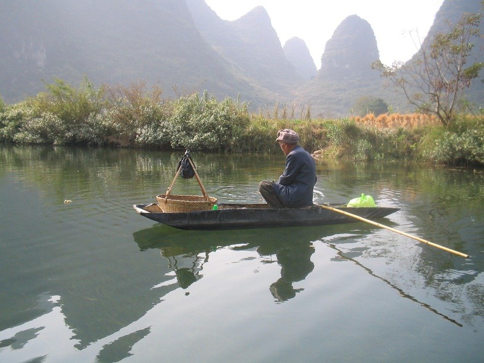 small boat on the river between the mountains in yangshuo