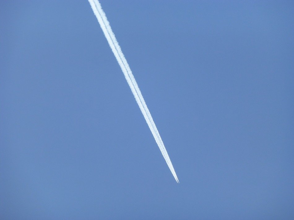 white plane trail in the blue sky