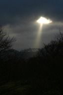 sunlight through the clouds of the dark sky