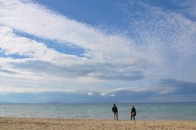 distant view of two people on the ocean beach