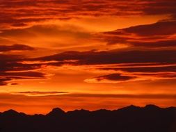 red sunset sky over black mountains