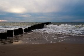 foamy sea waves splashing at breakwater on sand beach