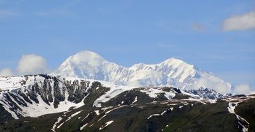 scenic snow capped denali mountain behind black rocks, usa, alaska