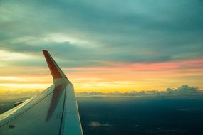 wing of an airplane against orange sky during an order