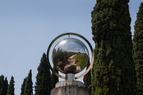 steel mirror ball near the Mediterranean cypress