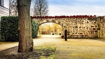 arched gateway in aged stone wall at fall, germany, kassel