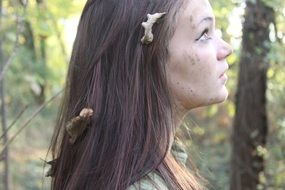 portrait of a frightened young girl with dry leaves in her hair in a forest