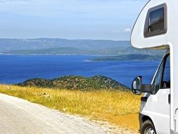 a car for camping travels along the road along the sea
