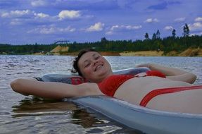 woman in a red bathing suit on an inflatable mattress on the water