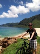 young man with bicycle on scenic seashore, usa, hawaii