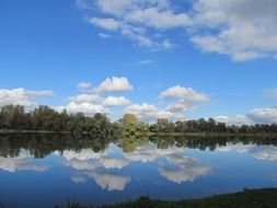 summer landscape of fluffy clouds mirroring on calm water