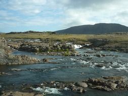 river flowing among rocks, distant mountains at skyline, iceland