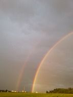 Beautiful and colorful double rainbow in cloudy sky