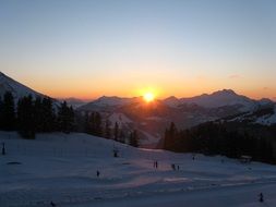 skiers in the mountains of france at sunset