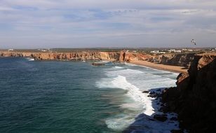 foamy surf in bay at rocky coast, portugal, algarve