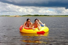 girls on an inflatable mattress on the water