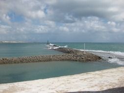 Landscape of cloudy sky over a stone breakwater
