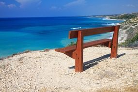 brown wooden bench on a sandy beach in Cyprus