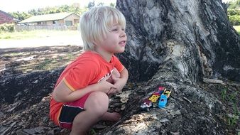 portrait of little child boy plays beneath tree