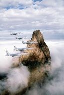 military planes flying at rock formation above clouds