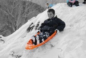 child boy riding sled from hill