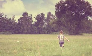 vintage photo of boy runs through a forest meadow