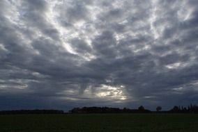 landscape of grey Clouds in the sky over a green field