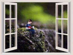 child is reading a book view through the window