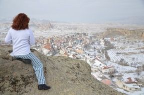 brunette sits on top of a mountain in Сappadocia