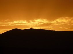 silhouette of radio tower on a hill at sunset