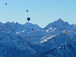 colored balloons over snowy mountains