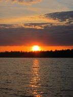 Beautiful and colorful sunset is reflected in the lake with the shore