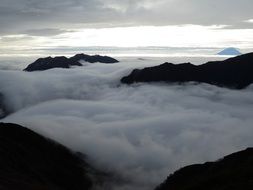 white clouds between dark mountain peaks, japan