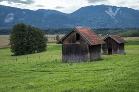 log cabins on a meadow in alpine mountains