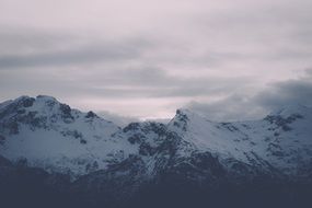 mountain tops in the snow under the clouds