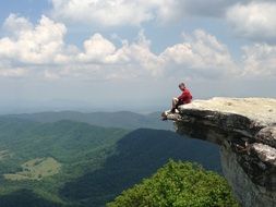 man is sitting on the edge of the cliff