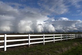 rain clouds white wooden fence pasture