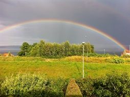 Beautiful multi-colored rainbow over a beautiful, colorful rural field with trees