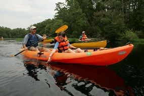 orange canoe boat with people on river