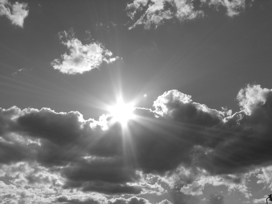 Black and white photo of bright Sun behind the clouds