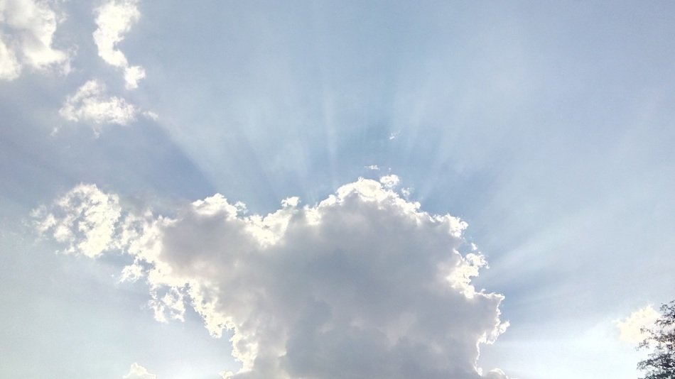 the sun behind the white cloud in the sky