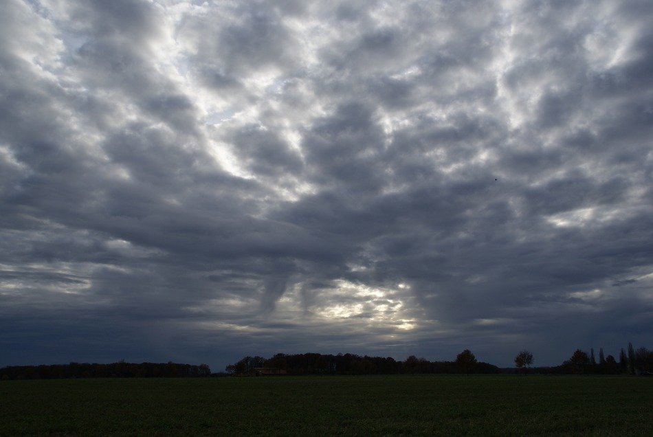 landscape of grey Clouds in the sky over a green field