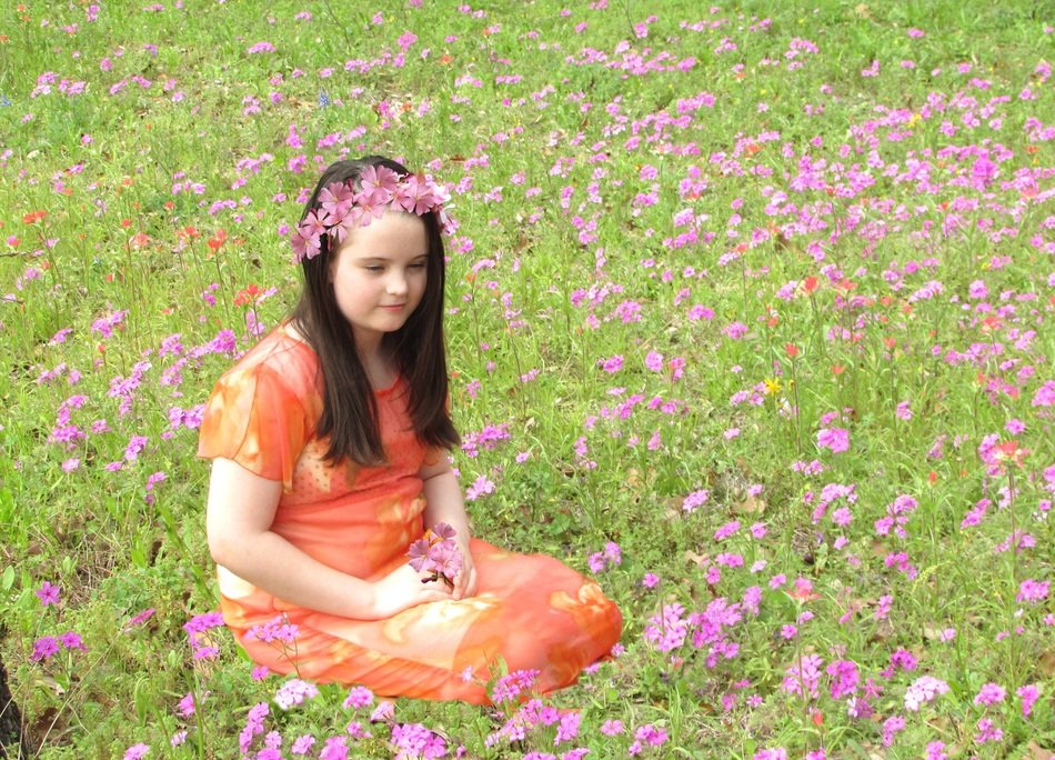 girl sitting on the field with pink flowers