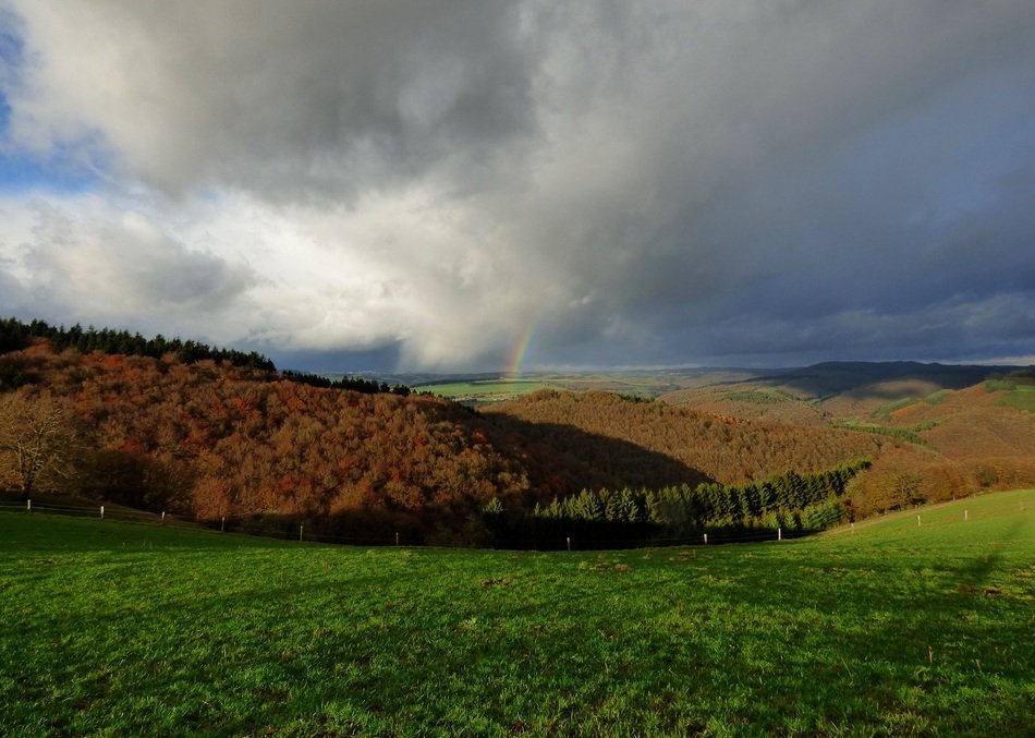 Beautiful rainbow and stormy sky over the colorful hills in Luxembourg
