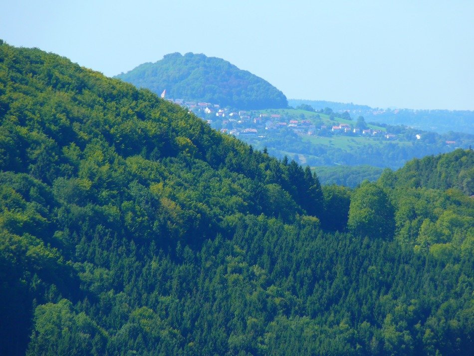 green hills on a background of high mountains in the haze