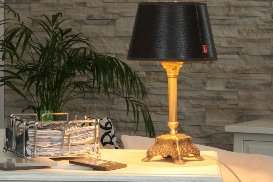 romantic style in the room, a beautiful desk lamp on the desk against the background of a stone wall