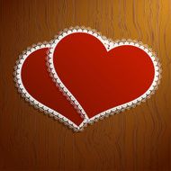 Two lacy red hearts on a wooden background